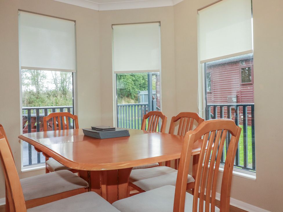 A dining room with a wooden table and chairs at Lodge 9 - Lamorna in Tregolds near St Merryn