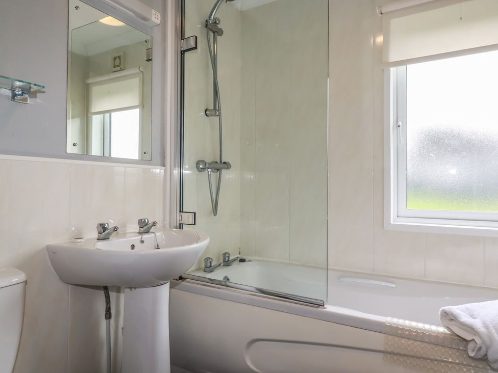 A bathroom with a bathtub, sink, and toilet at Lodge 9 - Lamorna Tregolds near St Merryn