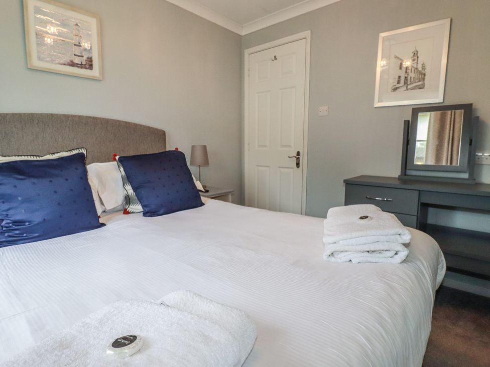 A bedroom with a bed, lamp, and mirror at Lodge 9 - Lamorna Tregolds near St Merryn
