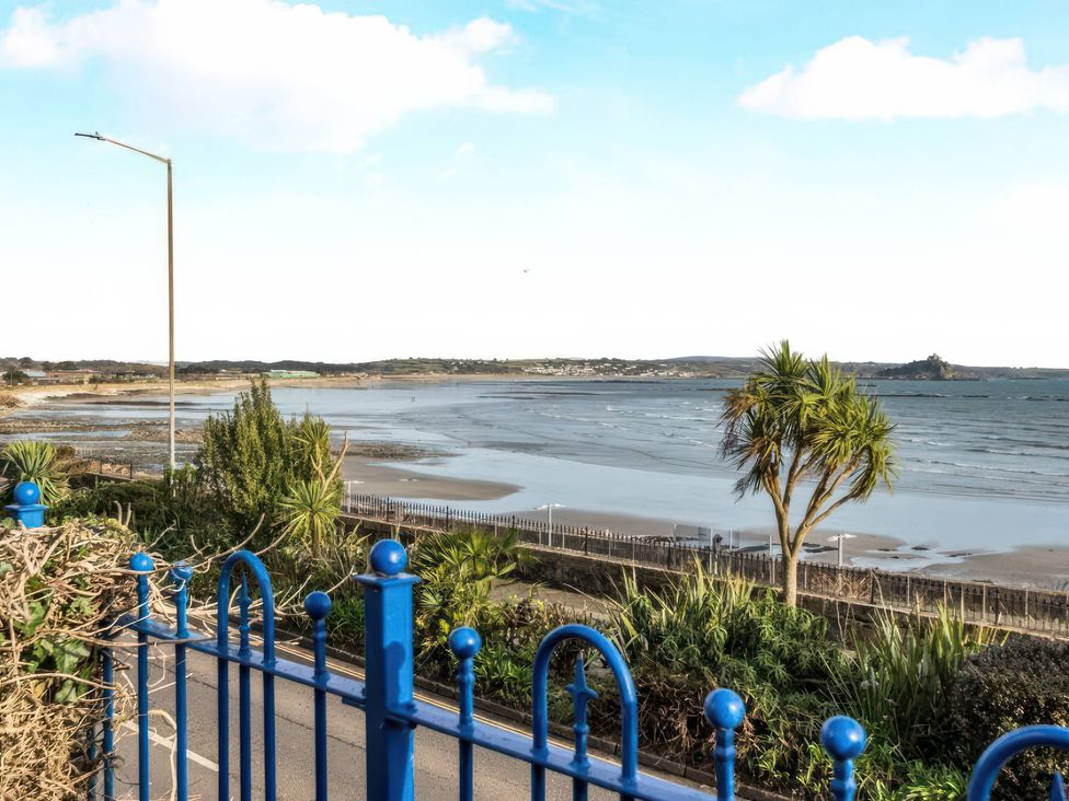 A view of the beach and sea with palm trees at 1 Penrose Court in Penzance