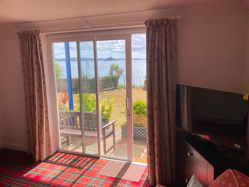 A living room with a view of the garden and sea at 1 Penrose Court in Penzance
