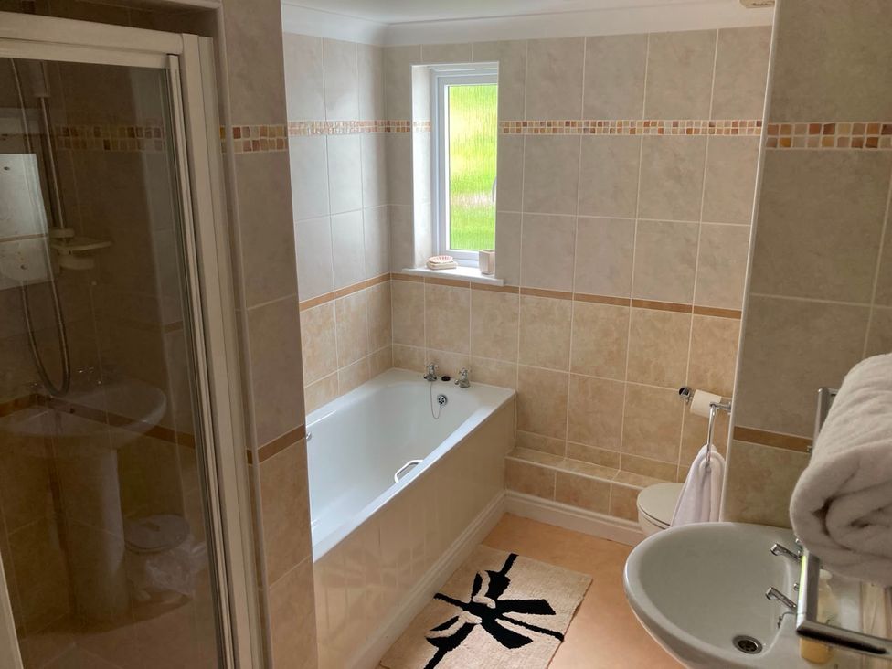 A bathroom with a bathtub, shower, sink, and toilet at 1 Penrose Court in Penzance