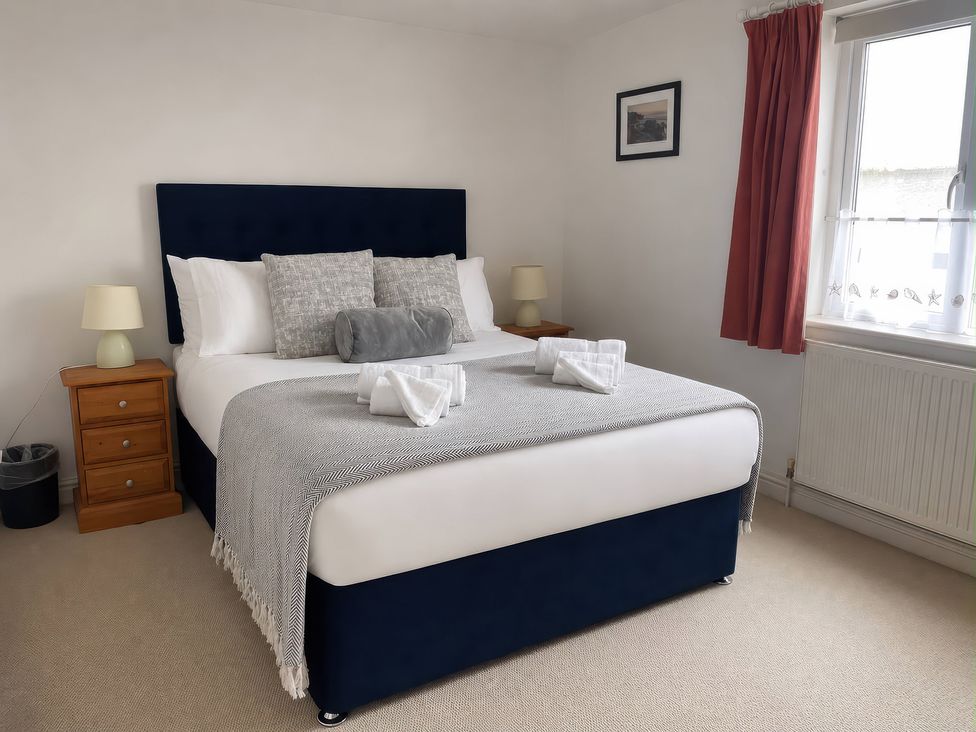 A bedroom with a bed and bedside tables at Tide Watch in Penzance