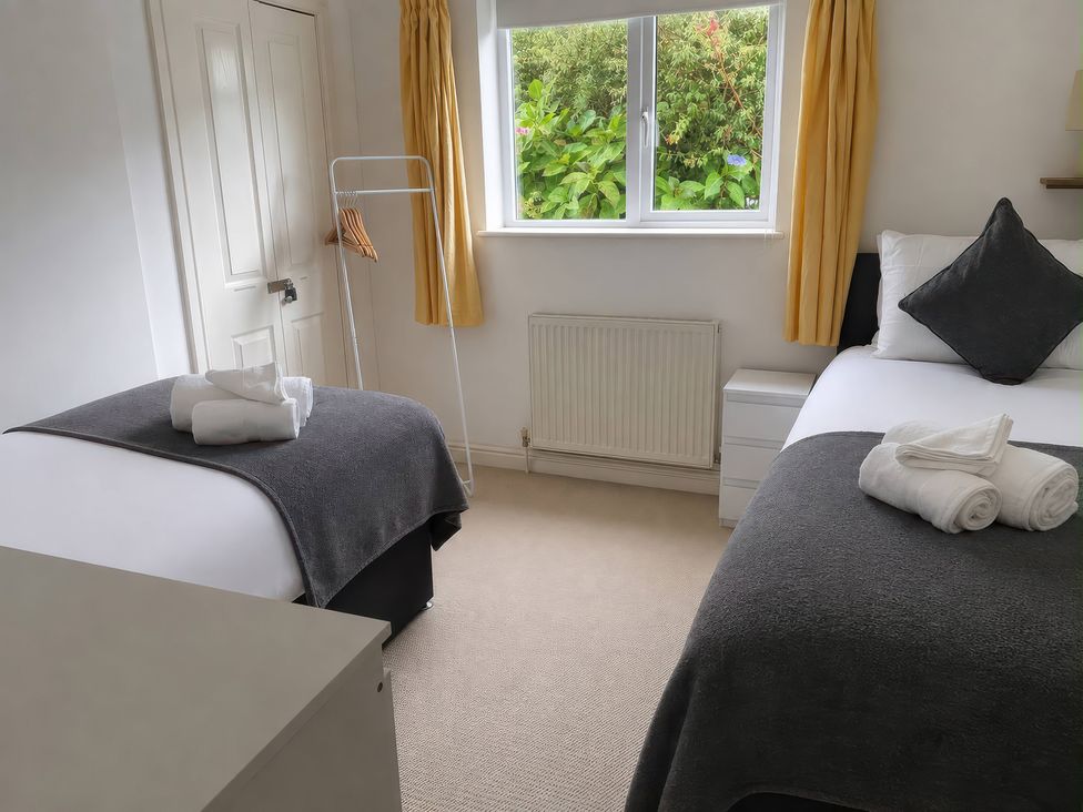 A bedroom with two beds arranged and towels on each bed at Tide Watch in Penzance