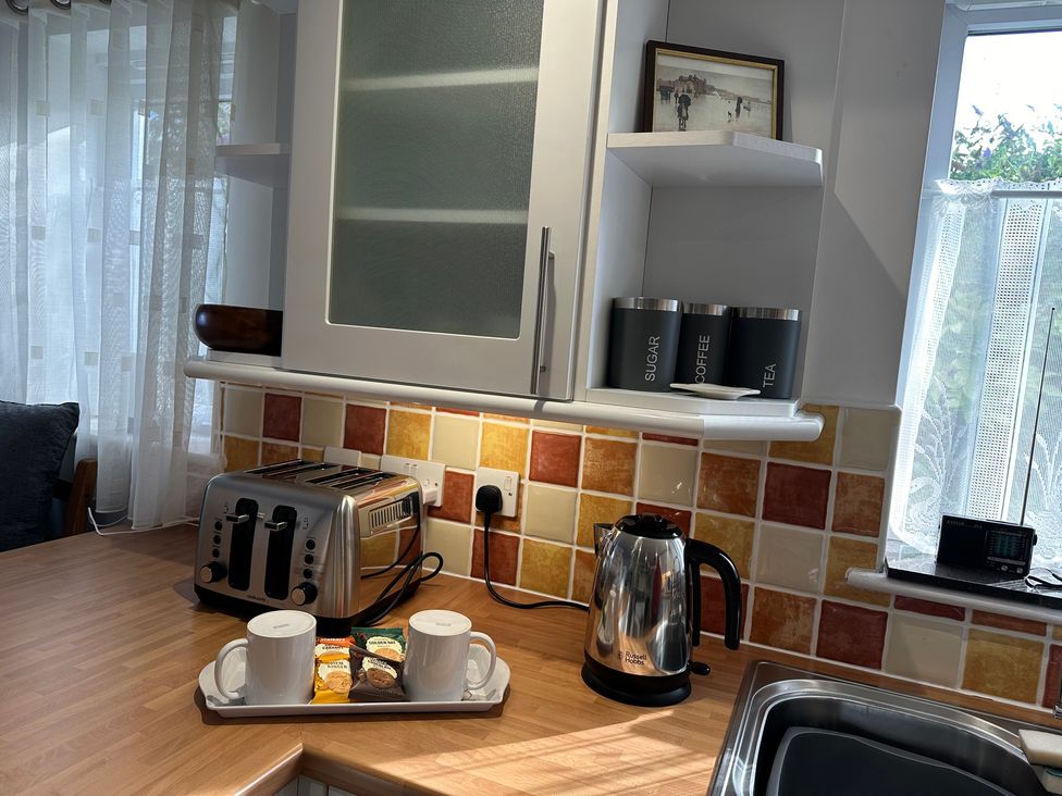 A kitchen with a kettle, toaster, cups, and storage containers at Tide Watch in Penzance
