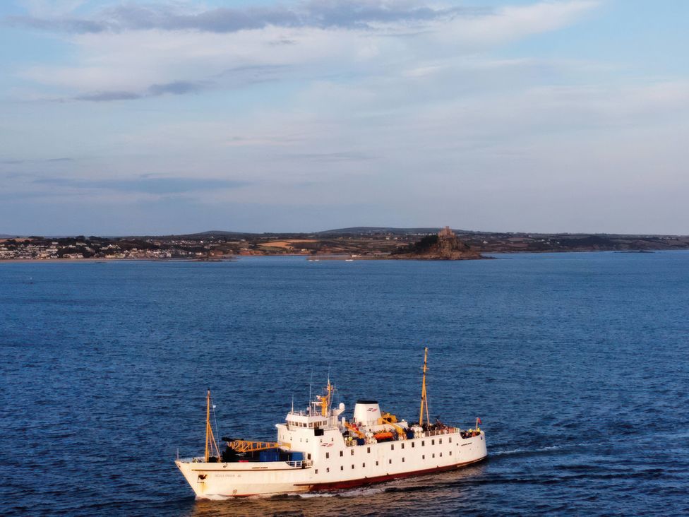 A ship sailing in the ocean near an island at Tide Watch in Penzance