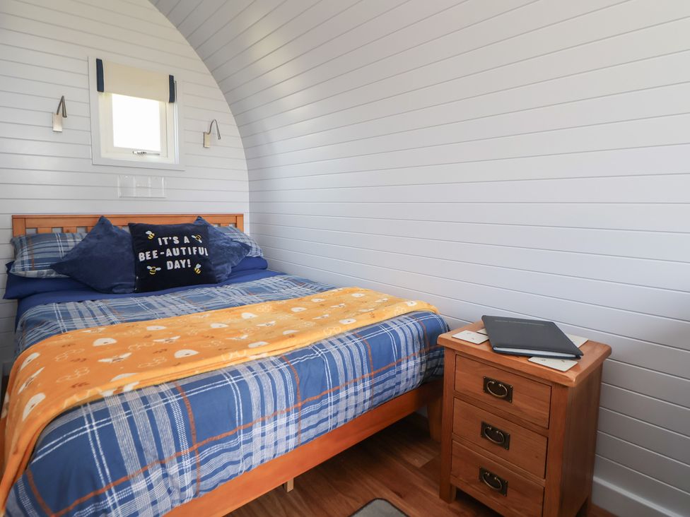 A bedroom with a bed and nightstand at Honeypot Hideaways - Acacia