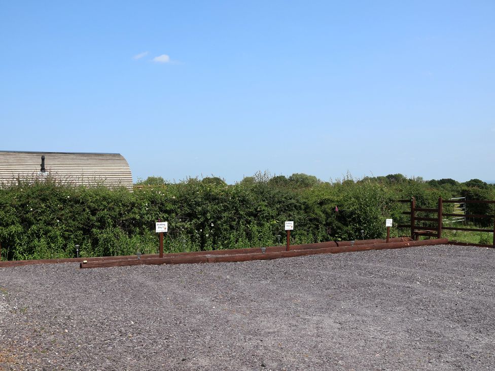 A parking area with gravel and signs at Honeypot Hideaways - Acacia