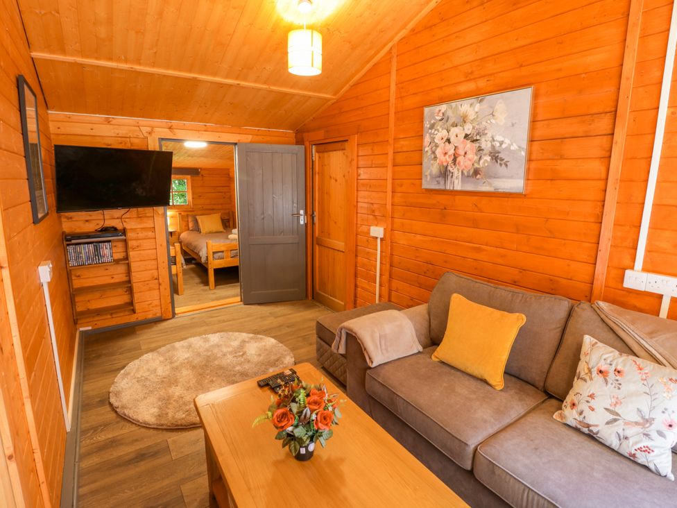 A living room with a sofa and television at Stumps Cross Lodge Upper Coscombe near Winchcombe