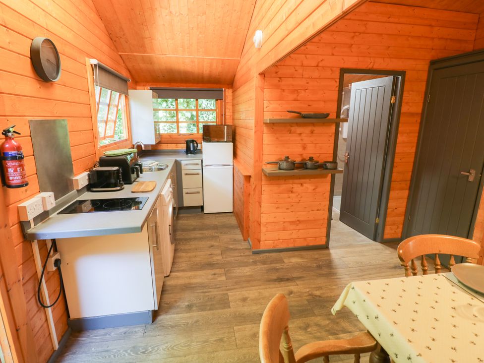 A kitchen with appliances and a breakfast table at Stumps Cross Lodge Upper Coscombe near Winchcombe