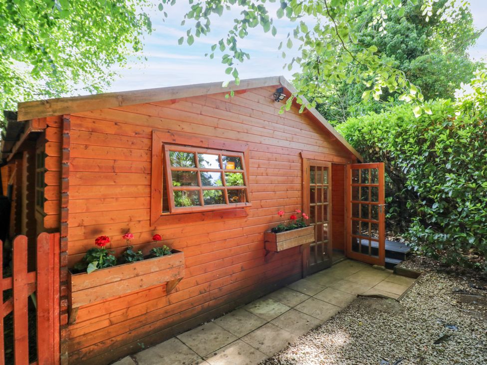 A wooden cabin with a gravel path and planters at Stumps Cross Lodge Upper Coscombe near Winchcombe