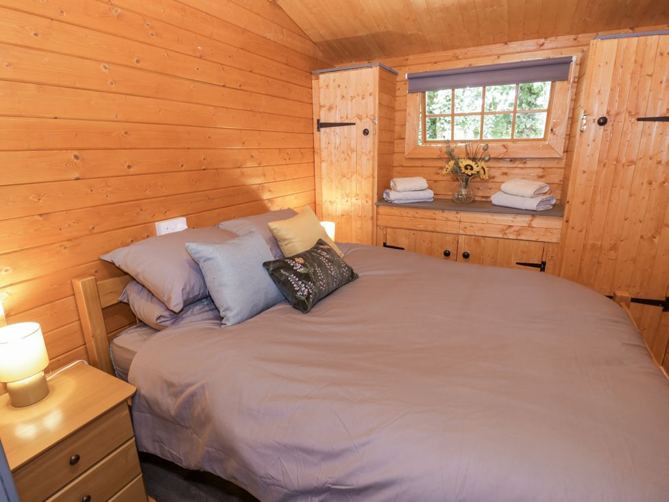 A bedroom with a bed and shelves at Stumps Cross Lodge Upper Coscombe near Winchcombe