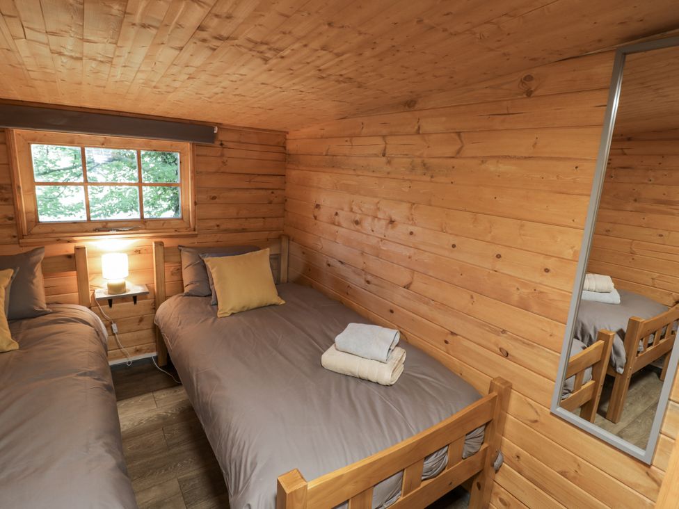 A bedroom with two single beds and a window at Stumps Cross Lodge Upper Coscombe near Winchcombe