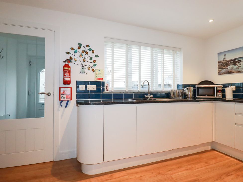 A kitchen with a sink, microwave, and fire extinguisher at Fistral Palms 2