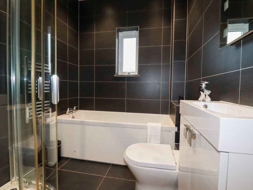 A bathroom with a bathtub, toilet, sink, and shower at Fistral Palms 2