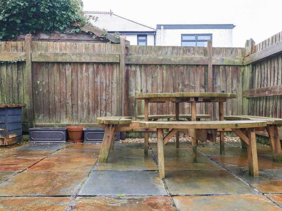 A garden with a wooden table and benches at Fistral Palms 2