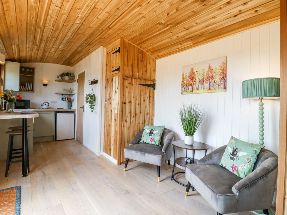 A seating area with two grey armchairs and a side table with a plant in Woodpecker in Lode near Bottisham