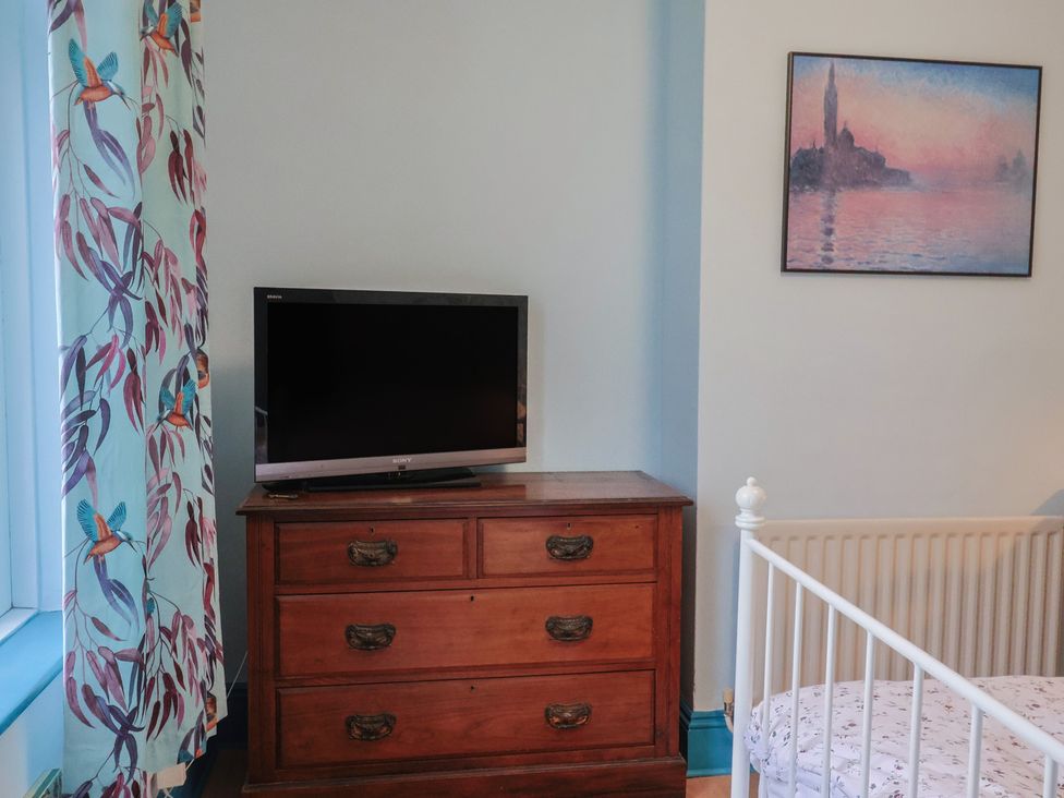 A bedroom with a television on a dresser and a crib at 20 Lym Close