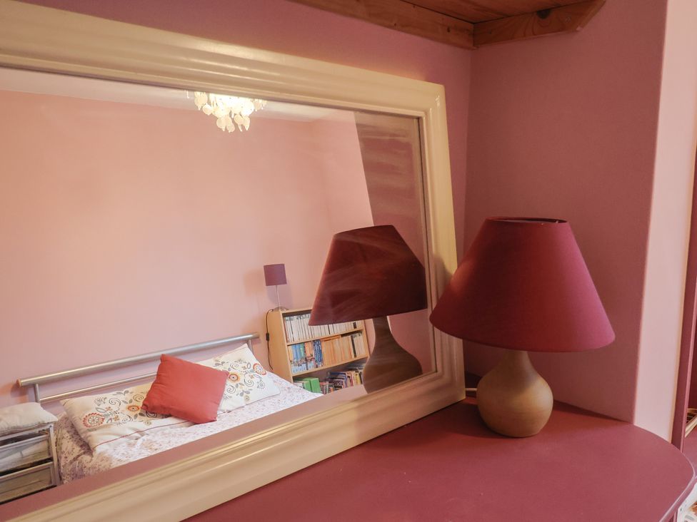 A bedroom with a bed and lamp reflected in a mirror at 20 Lym Close