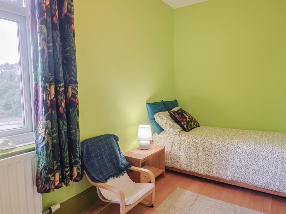 A bedroom with a bed, lamp, chair and curtains at 20 Lym Close