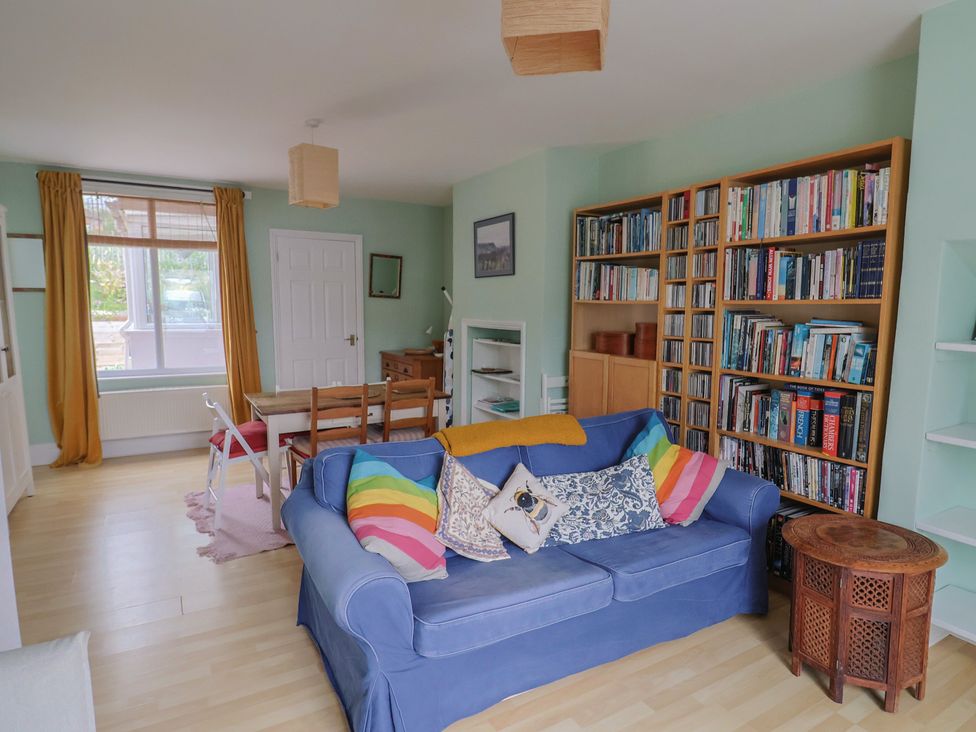 A living room with bookshelves and a dining table at 20 Lym Close in Lyme Regis