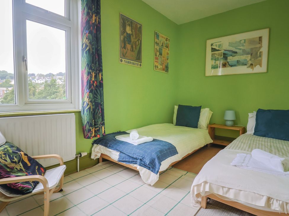 A bedroom with two beds and a chair at 20 Lym Close in Lyme Regis