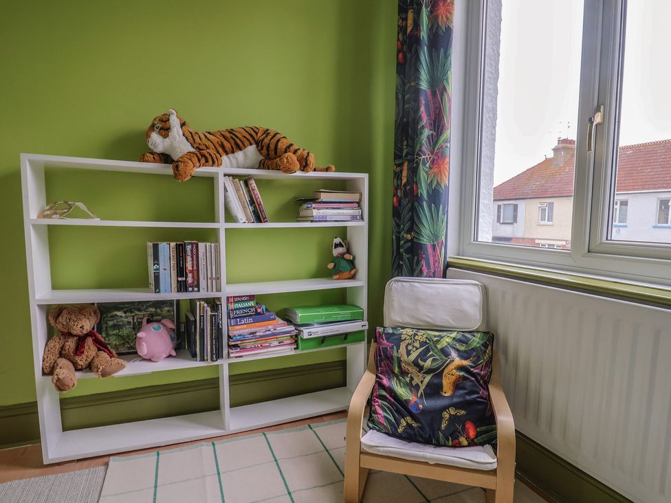A room with a bookshelf and chair at 20 Lym Close in Lyme Regis