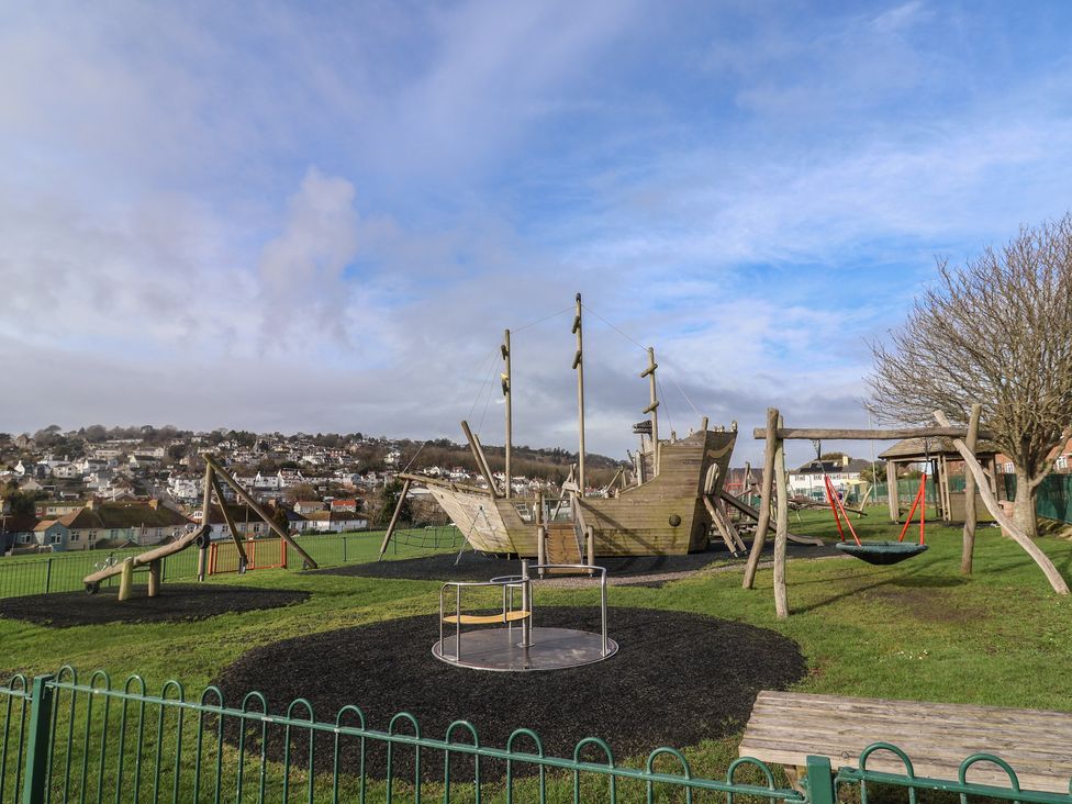 A playground with a ship play structure and swings at 20 Lym Close in Lyme Regis
