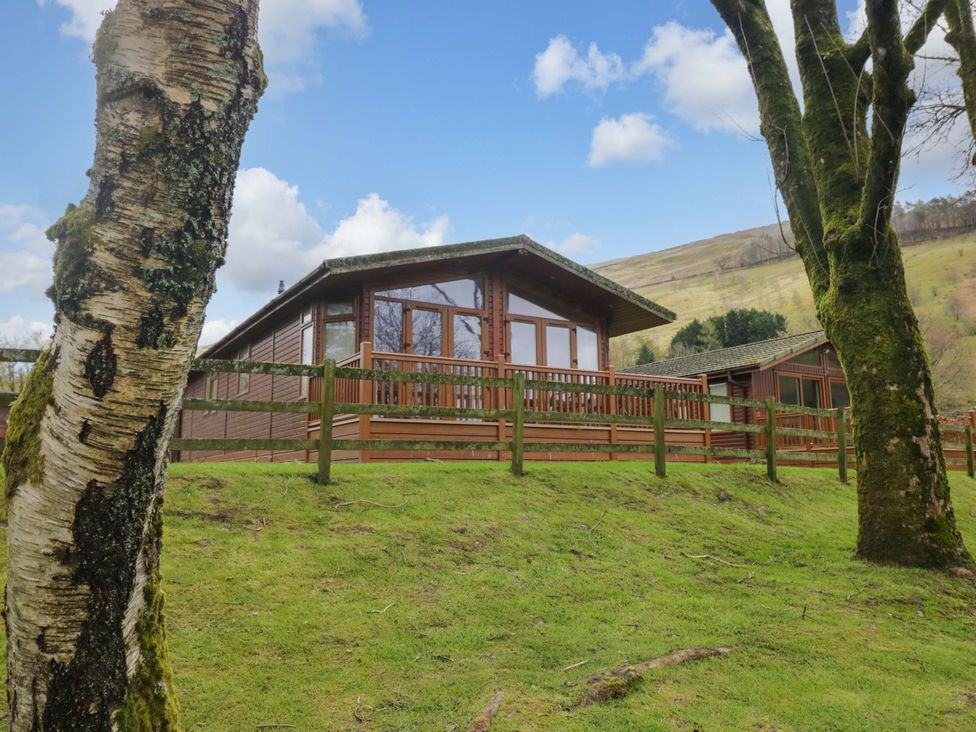 A log cabin with a deck and trees at Wansfell 2 Limefitt Park near Troutbeck