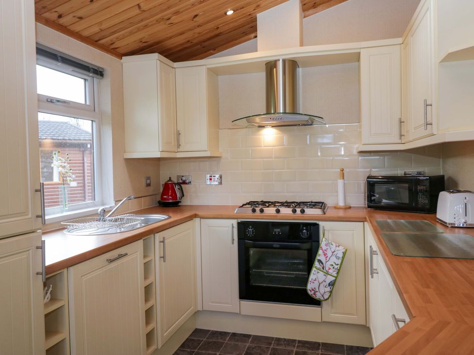 A kitchen with cabinets, cooking range, sink, and microwave at Wansfell 2 in Limefitt Park near Troutbeck