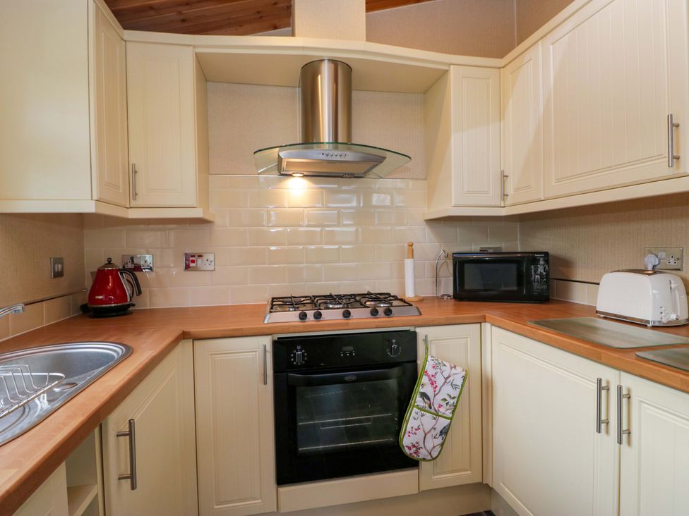 A kitchen with a cooker, microwave, and kettle at Wansfell 2 Limefitt Park near Troutbeck