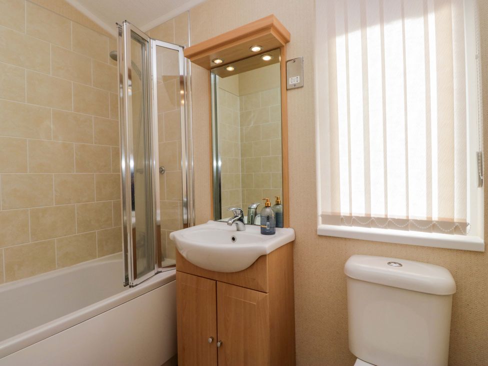 A bathroom with a bathtub, shower, sink, and toilet at Wansfell 2 Limefitt Park near Troutbeck