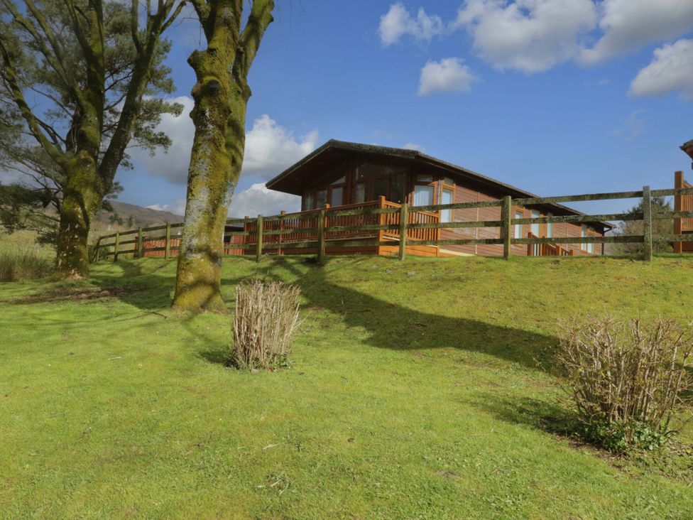 A house with a wooden fence and trees at Wansfell 2 in Limefitt Park near Troutbeck
