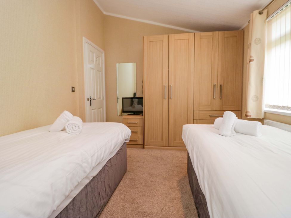A bedroom with two beds and a wardrobe at Wansfell 2 in Limefitt Park near Troutbeck