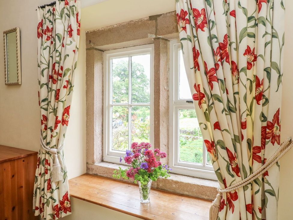 A window with curtains and a vase of flowers at Orchard View in Ashbourne