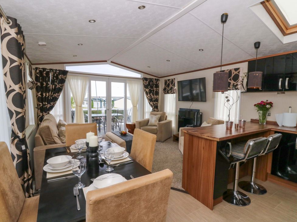 A living room with a dining area and kitchen counter at Ty Seren in New Quay