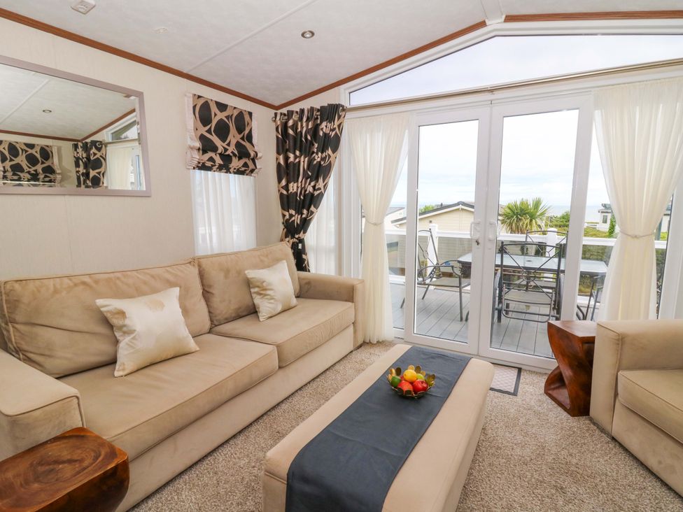 A living room with sofa and sliding doors at Ty Seren in New Quay