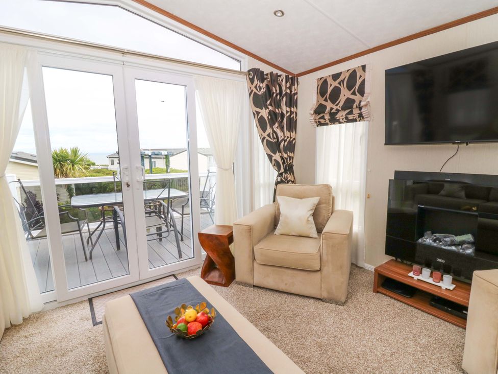 A living room with double doors leading to a deck at Ty Seren in New Quay
