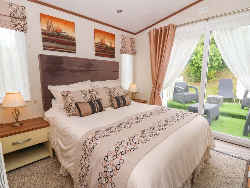 A bedroom with a bed and window leading outside at Ty Seren in New Quay