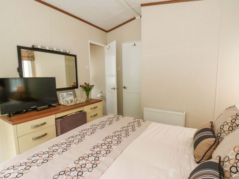 A bedroom with a bed and television at Ty Seren in New Quay