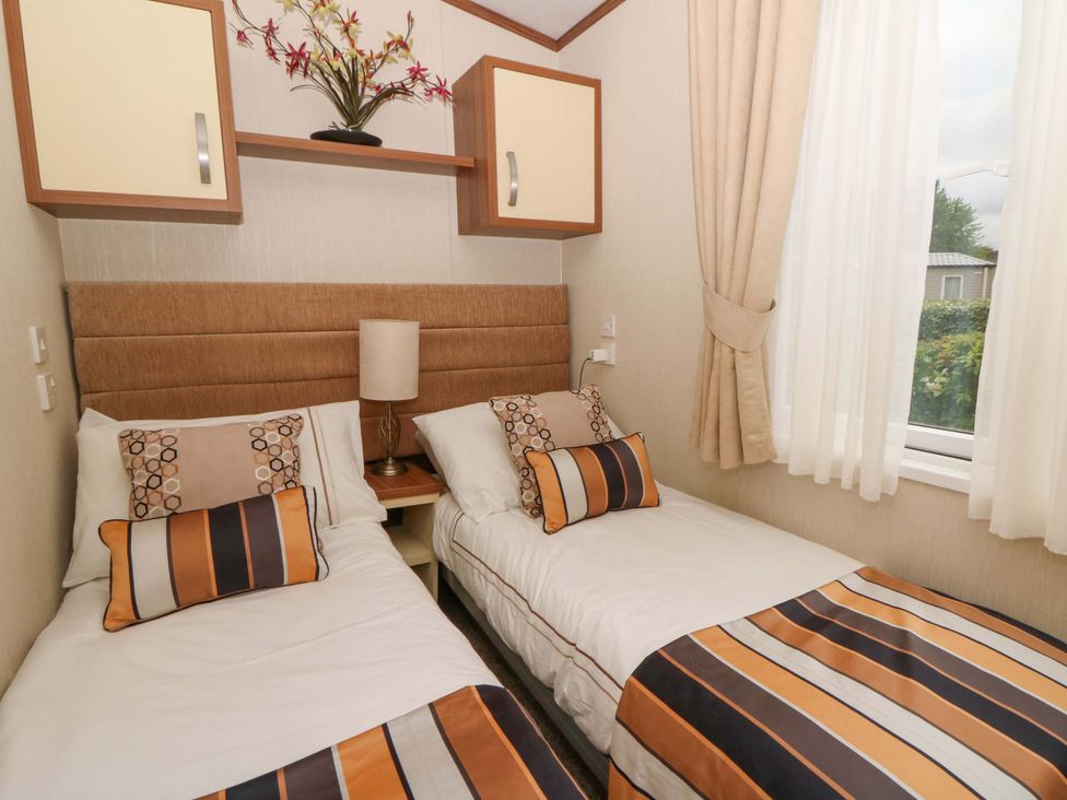 A bedroom with twin beds and a bedside lamp at Ty Seren in New Quay