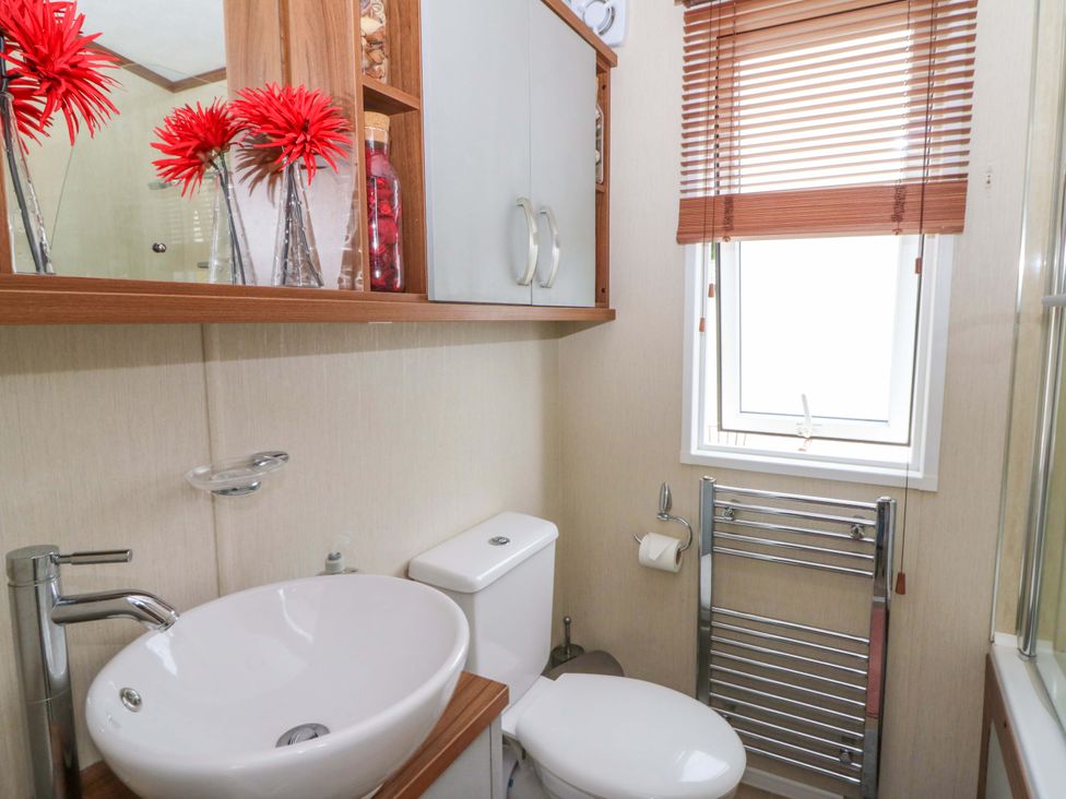 A bathroom with a sink, toilet, and mirror at Ty Seren in New Quay