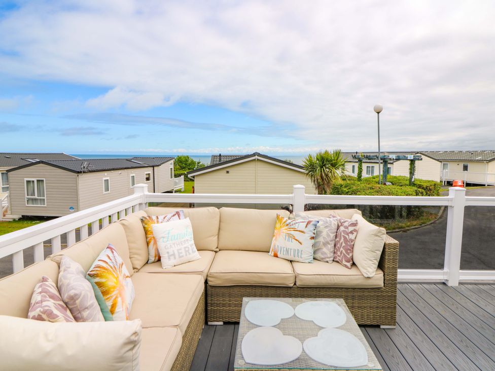 An outdoor area with a sofa and table overlooking a landscape at Ty Seren in New Quay