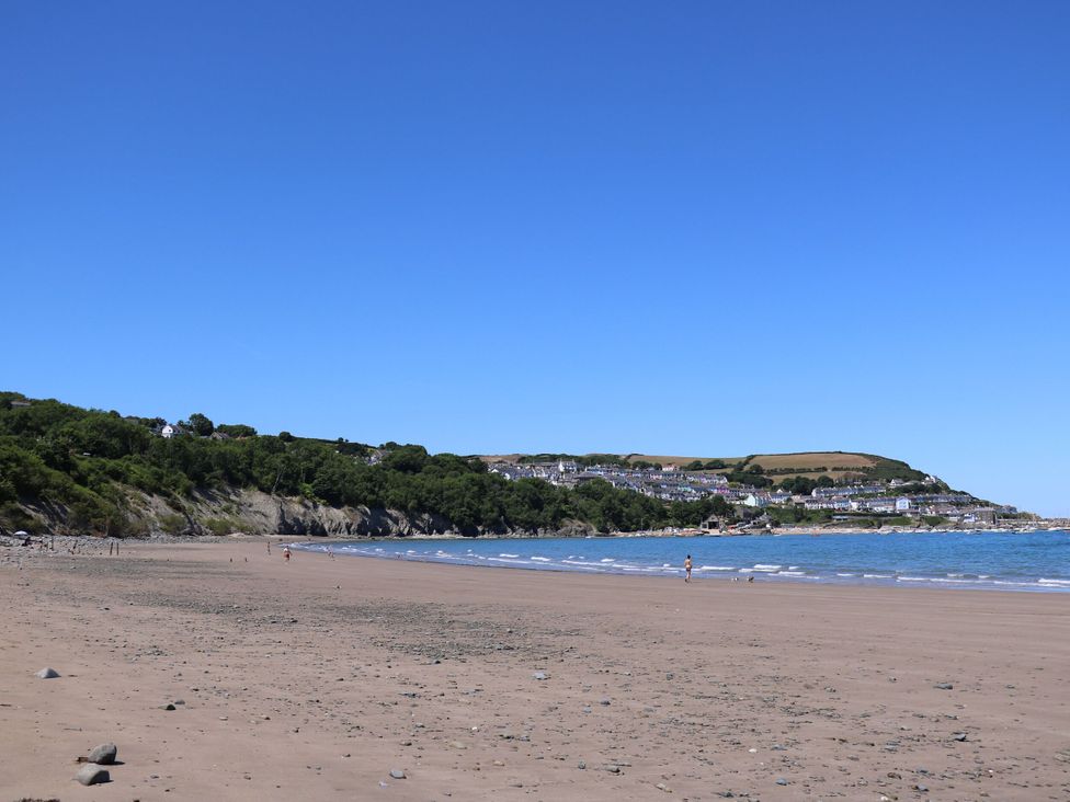 A beach with water and cliffs in the background at Ty Seren in New Quay