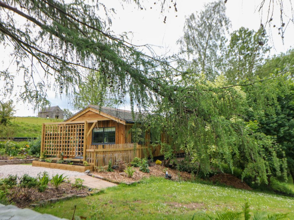 A wooden cabin with a garden and gravel path at Stoney Rock Lodge