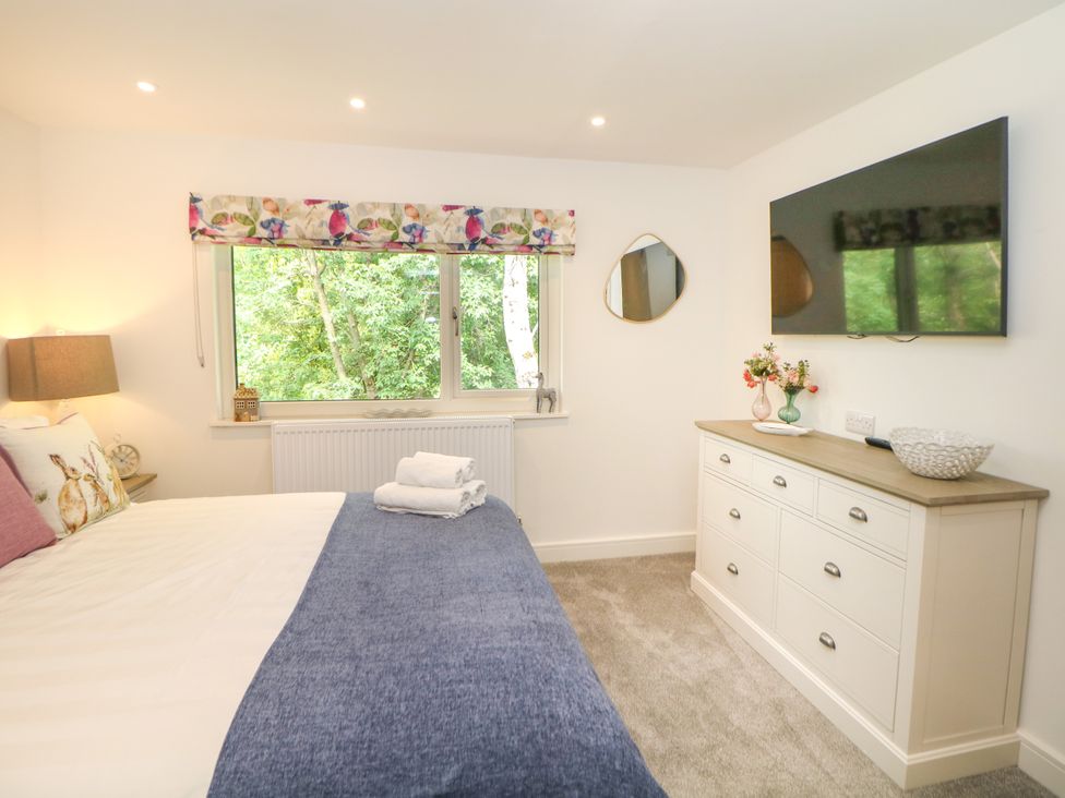 A bedroom with a bed, dresser, and television at Stoney Rock Lodge