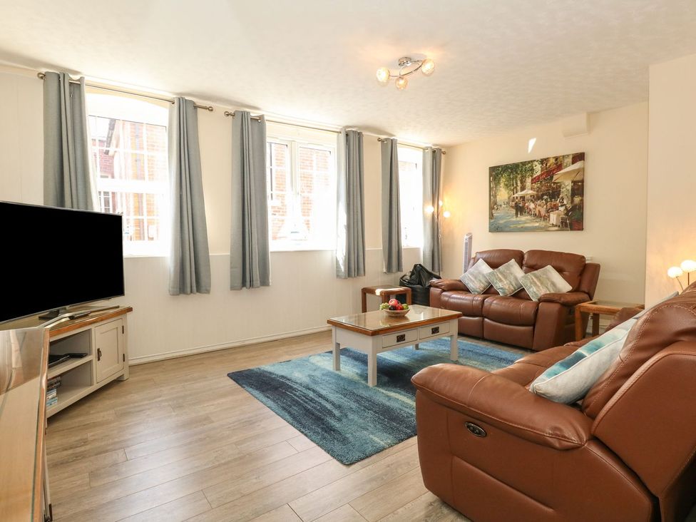 A living room with brown leather sofas a coffee table and a television at Old Malthouse Apartment in Weymouth