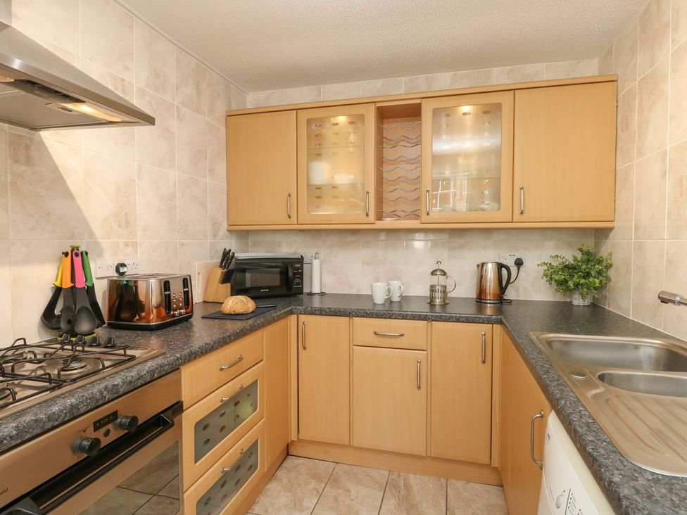 A kitchen with wooden cabinets toaster microwave and sink at Old Malthouse Apartment Weymouth