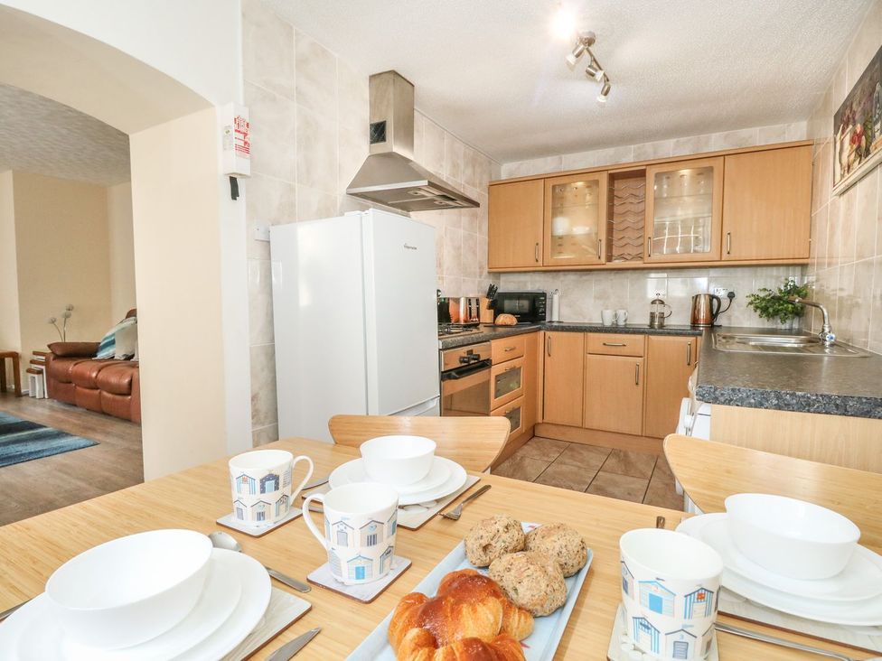 A kitchen with wooden cabinets a dining table set with cups plates and bread at Old Malthouse Apartment in Weymouth