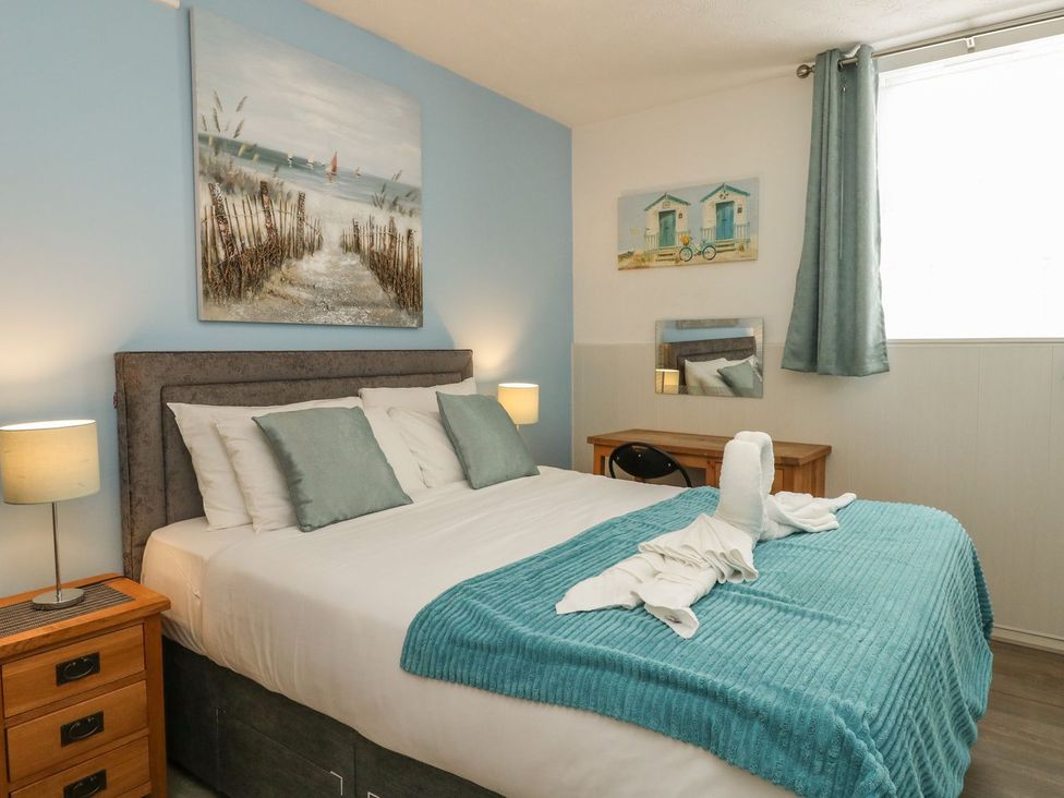 A bedroom with a double bed side tables lamps a desk chair and paintings at Old Malthouse Apartment in Weymouth
